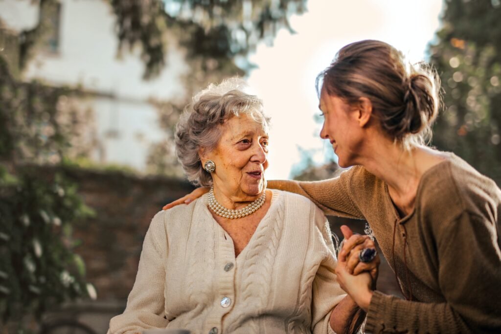 This is an image of an carer talking to an elderly woman on a bench.